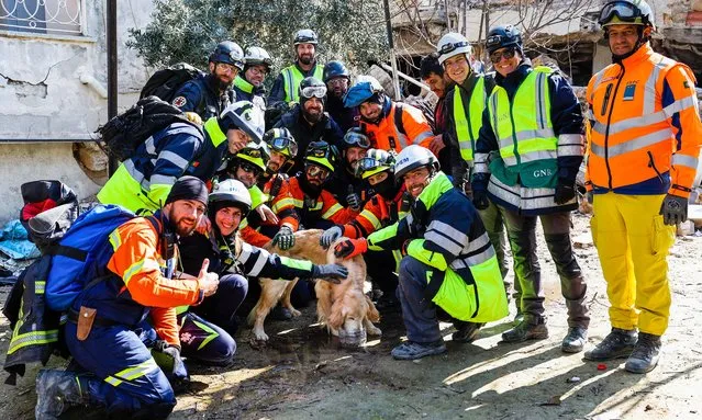Portuguese rescue team members pose for a photo with dog named Tarcin (Cinnamon) saved from a building that collapsed during the earthquake in Antakya capital of Hatay Province, Turkey, 14 February 2023. (Photo by Joao Relvas/EPA/EFE)