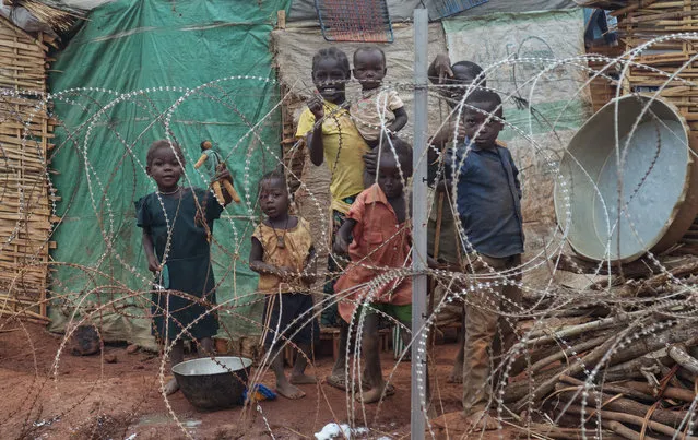 In this Sunday, May 14, 2017 file photo, a displaced family stands behind the razor-wire that surrounds the United Nations' protected camp in Wau, South Sudan. (Photo by Sam Mednick/AP Photo)