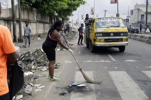 Volunteers sweep burnt out tyres on the roads in Lagos Saturday, October 24, 2020. Nigeria's president says 51 civilians have been killed in unrest following days of peaceful protests over police abuses, and he blames “hooliganism” for the violence while asserting that security forces have used “extreme restraint”. (Photo by Sunday Alamba/AP Photo)