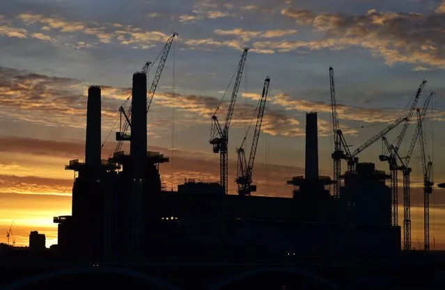 Battersea Power Station is seen at dawn, surrounded by cranes and with one of it's four iconic chimneys missing, in London, December 9, 2014. The decommissioned coal-fired power station, not used since 1983, is being redeveloped into retail, office and residential use over the next four years. One of the planning requirements is the preservation of the character of the original building, which involves taking down each chimney and wash tower and then rebuilding them. (Photo by Toby Melville/Reuters)