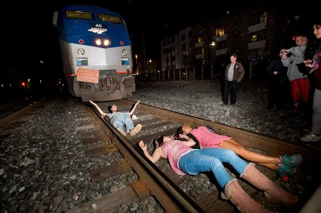 Protesters block an Amtrak train in Berkeley, Calif., on Monday, December 8, 2014. Hundreds of people marched through Berkeley for a third night, blocking an interstate highway and stopping the train as activists rallied against grand jury decisions not to indict white police officers in the deaths of two unarmed black men. (Photo by Noah Berger/AP Photo)