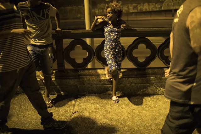 In this January 22, 2018 photo, a girl watches the Paraiso do Tuiuti samba school rehearse their dances and songs, which this year make reference to Brazil's history with slavery, in the streets of Rio de Janeiro, Brazil. Brazil was the last country in the Americas to abolish slavery, and 130 years later the impact is still very much felt in this content-size nation. (Photo by Leo Correa/AP Photo)