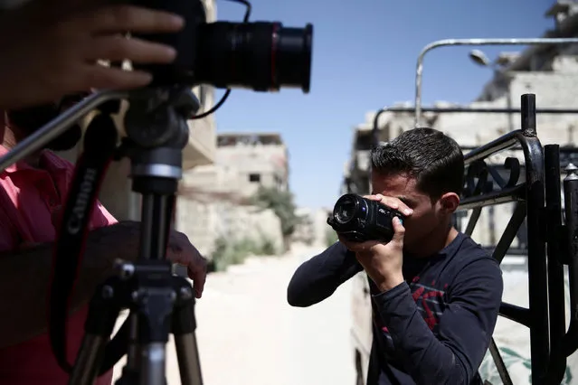 A young man films behind-the-scenes of a film directed by Humam Husari in the rebel-held besieged town of Zamalka, in the Damascus suburbs, Syria September 19, 2016. (Photo by Bassam Khabieh/Reuters)