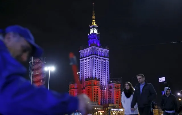 People walk in front of the Palace of Culture, which is lighted up in France's national colours after last night's attacks in Paris, in Warsaw, Poland November 14, 2015. (Photo by Kacper Pempel/Reuters)