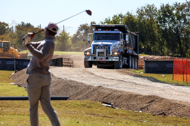 A golfer tees off as a dump truck exits a makeshift dump site after dropping soil and debris from the East Wing of the White House, where U.S. President Donald Trump's proposed ballroom is being built, at the East Potomac Golf Course in Washington, D.C., U.S., October 23, 2025. (Photo by Jessica Koscielniak/Reuters)