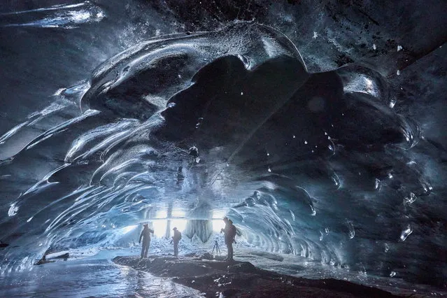People stand in the “Mill”, a 20m long natural ice cave created by melted water accumulated during the summer and by a siphon effect leaves in the autumn giving way to an ice cathedral, at the Glacier 3000 ski resort in Les Diablerets, Switzerland, December 10, 2020. (Photo by Denis Balibouse/Reuters)