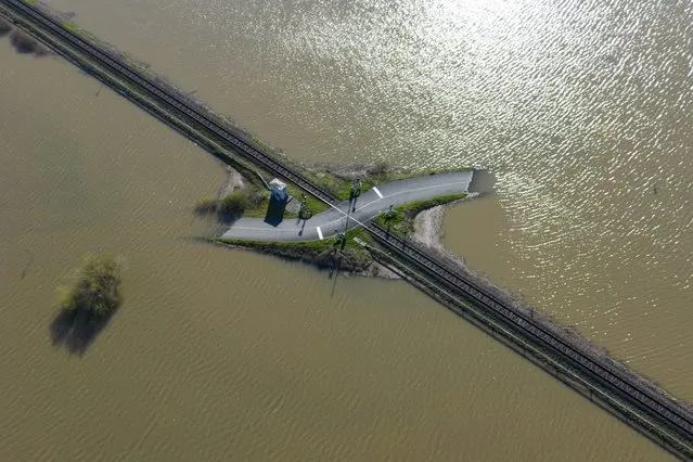 A railroad crossing lies in the middle of a flooded meadow, in Nidderau, Germany, Monday, April 3, 2023. After days of rain, large areas in the lowlands are flooded. (Photo by Boris Roessler/dpa via AP Photo)