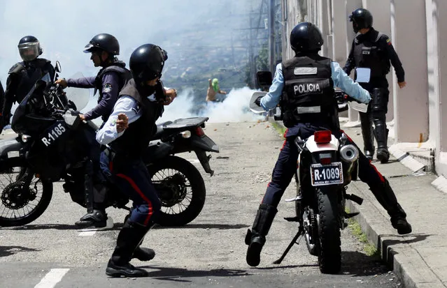 A riot police officer throws a stone during clashes with opposition supporters in a rally to demand a referendum to remove President Nicolas Maduro in San Cristobal, Venezuela October 24, 2016. (Photo by Carlos Eduardo Ramirez/Reuters)