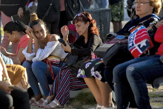 People wait in a park to be called on by the nearby U.S. embassy on the day of its reopening for visa and consular services in Havana, Cuba, Wednesday, January 4, 2023. (Photo by Ismael Francisco/AP Photo)