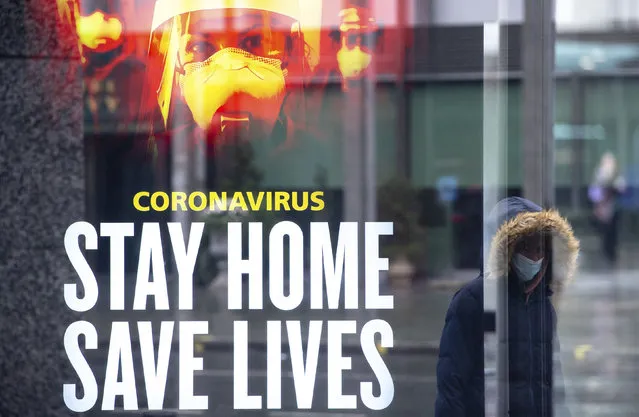A woman passes a government conronavirus advert in central London, during England's third national lockdown to curb the spread of coronavirus, Thursday, January 14, 2021. (Photo by Dominic Lipinski/PA Wire via AP Photo)