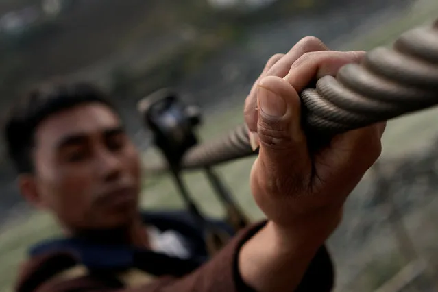 A man from Lazimi village pulls himself back to the ground after zipping across the Nu River in Nujiang Lisu Autonomous Prefecture in Yunnan province, China, March 24, 2018. Chinese mountain villagers, cut off from shops and churches by a raging river, use a zipline to cross its violent rapids and jagged rocks. (Photo by Aly Song/Reuters)