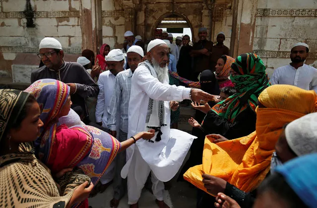 A Muslim man gives alms to the poor at a mosque during Jumat-ul-Vida or the last Friday of the holy fasting month of Ramadan, in Ahmedabad, India, June 15, 2018. (Photo by Amit Dave/Reuters)