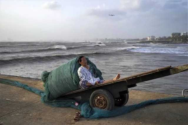 A woman takes rest on a handcart as high tide waves hit the Arabian Sea coast at Juhu Koliwada in Mumbai, India, Monday, June 12, 2023. (Photo by Rafiq Maqbool/AP Photo)