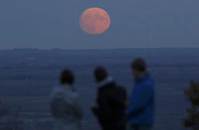 A family watch the moon rise a day before the “supermoon” spectacle on Beacon Hill near Loughborough, Britain, November 13, 2016. (Photo by Darren Staples/Reuters)