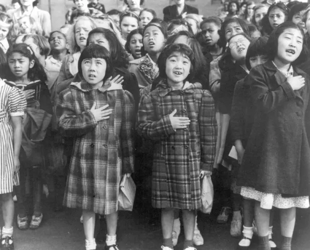 In this April 1942 file photo made available by the Library of Congress, children at the Weill public school in San Francisco recite the Pledge of Allegiance. Some of them are evacuees of Japanese ancestry who will be housed in War Relocation Authority centers for the duration of World War II. Throughout American history, during times of war and unrest, authorities have cited various reasons and laws to take children away from their parents. Examples include Native American boarding schools, Japanese internment camps and deportations that happened during the Great Depression. (Photo by Dorothea Lange/U.S. War Relocation Authority via AP Photo)