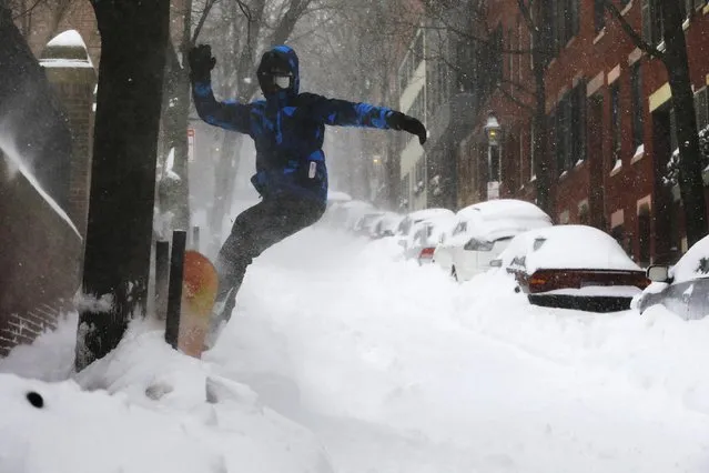 Fourteen-year-old Will Adam snow boards down a street on Beacon Hill during a large winter blizzard in Boston, Massachusetts January 27, 2015. (Photo by Brian Snyder/Reuters)