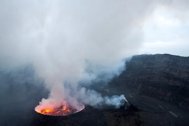 A lava lake and a mini cone inside the Mount Nyiragongo volcano crater spew gas into the sky inside the Virunga National Park, near Goma, in the eastern Democratic Republic of Congo February 11, 2021. Volcano watchers worry that volcanic activity observed in the last five years mirrors that in the years preceding the 1977 and 2002 eruptions. (Photo by Hereward Holland/Reuters)