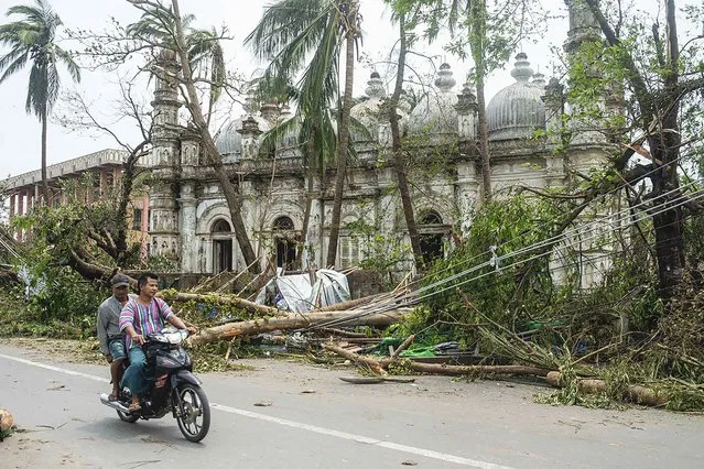 Locals ride motorbike on a road while fallen trees lie near a mosque after Cyclone Mocha in Sittwe township, Rakhine State, Myanmar, Monday, May 15, 2023. (Photo by AP Photo/Stringer)
