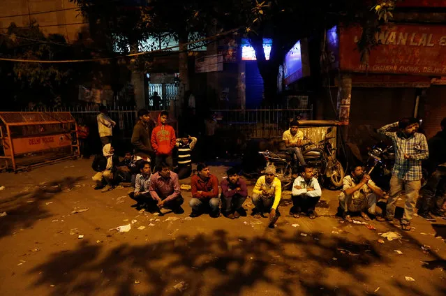 People sit in a queue as they wait for the bank to open to exchange their old high-denomination banknotes in the early hours, in the old quarters of Delhi, India, November 16, 2016. (Photo by Adnan Abidi/Reuters)