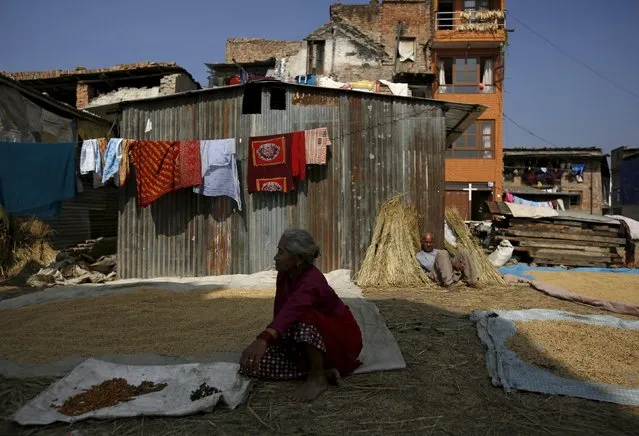 Earthquake victims sit in the sun to keep warm near their temporary shelters built close to houses damaged during an earthquake earlier this year, in Bhaktapur, Nepal November 19, 2015. (Photo by Navesh Chitrakar/Reuters)