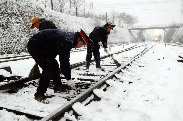 Railway workers clean the snow off a railway track at a station amid heavy snowfall in Xinmi, Henan province, January 28, 2015. Chinese government has signalled that it is keen to plough more cash into infrastructure both domestically and abroad as the economy slows, spurring the sector's stocks to their highest level since 2009. (Photo by Reuters/Stringer)