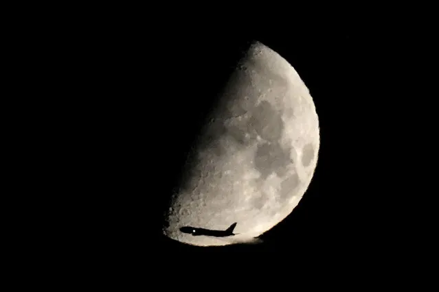 A commercial airliner crosses in front of a Waxing Gibbous moon after taking off from Midway International Airport heading east, Thursday, August 24, 2023, in Chicago. (Photo by Charles Rex Arbogast/AP Photo)