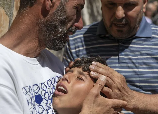Palestinian Wael Bernat, left, comforts his crying son Ahmad during the funeral of his other son Islam Bernat, 16, in the West Bank city of Ramallah, Wednesday, May 19, 2021. Multiple protesters were killed and more than 140 wounded in clashes with Israeli troops in Ramallah, Bethlehem, Hebron and other cities on Tuesday, according to the Palestinian Health Ministry. The Israeli army said at least a few soldiers were wounded in Ramallah by gunshots to the leg. (Photo by Nasser Nasser/AP Photo)