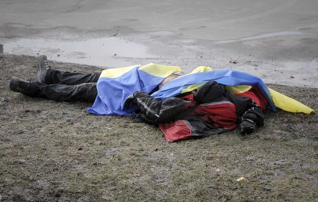 ATTENTION EDITORS - VISUAL COVERAGE OF SCENES OF INJURY OR DEATH
The body of a victim covered by Ukrainian national flags is seen at the site of an attack in Kharkiv, February 22, 2015. At least two people were killed and 10 wounded on Sunday when an explosive device was thrown from a car into a crowd attending a peace rally in the northeastern Ukrainian city of Kharkiv, Ukrainian officials said.  REUTERS/Stanislav Belousov (UKRAINE - Tags: MILITARY CONFLICT CIVIL UNREST)