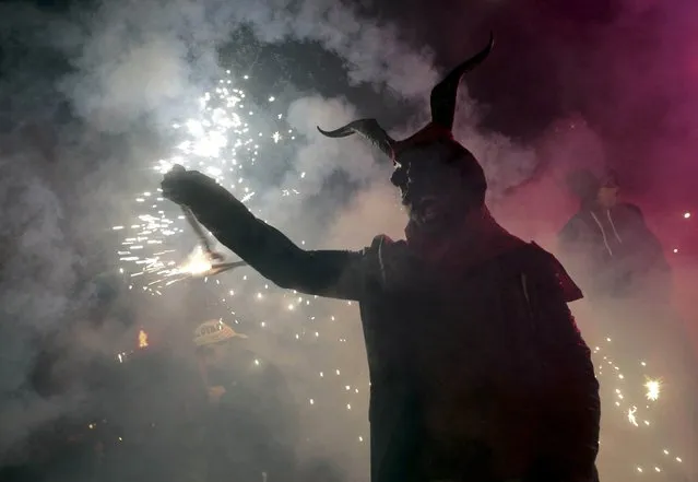 A reveller dressed as a devil holds a stick with fireworks during traditional “Correfocs” (fire runs) to mark the end of the local festivities in Palma, on the Spain's Balearic Island of Mallorca, January 23, 2016. “Correfocs” are traditional celebrations in eastern Spain with people dressed as dancing devils while lighting fireworks among crowds of spectators. (Photo by Enrique Calvo/Reuters)