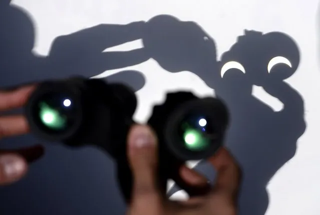 A person uses a pair of binoculars to watch the moon pass infront of the Earth's star marking a total eclipse, the only one this year, in Vigo, northwestern Spain on March 20, 2015. The Norwegian archipelago of Svalbard, located 1,300 kilometres (800 miles) from the North Pole, is along with the Faroe Islands the only place the total eclipse will be visible, assuring three minutes of total darkness when the moon totally blocks the sun. (Photo by Miguel Riopa/AFP Photo)