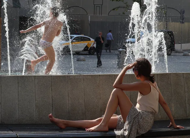 A woman sits by a fountain in central Moscow, Russia on June 23, 2021. (Photo by Sergei Fadeichev/TASS)