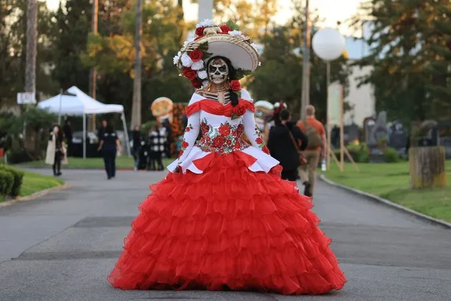 A woman walks the grounds in costume as revellers celebrate Dia De Los Muertos (Day of the Dead) at Hollywood Forever Cemetery in Los Angeles, California, on October 28, 2023. Every year on the last Saturday before November 2nd, Hollywood Forever Cemetery welcomes members of the community to celebrate Dia de Los Muertos, which reunites and honors beloved ancestors, family, and friends. (Photo by David Swanson/AFP Photo)