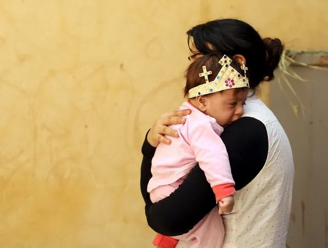 An Egyptian Coptic Christian carries her baby who wears a palm decoration during Palm Sunday inside a church in Old Cairo, April 5, 2015. (Photo by Asmaa Waguih/Reuters)