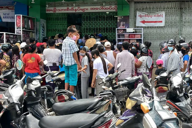 People wait outside a shop where face masks and vitamins are being given away in Mandalay, Myanmar, Thursday, July 8, 2021. (Photo by AP Photo/Stringer)