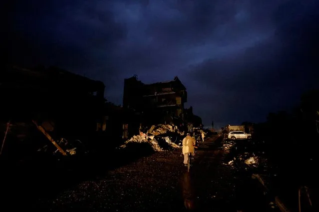 A Palestinian rides a bicycle next to the rubble of a house hit in an Israeli strike during the conflict, amid a temporary truce between Hamas and Israel, in Khan Younis in the southern Gaza Strip on November 27, 2023. (Photo by Mohammed Salem/Reuters)