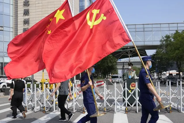 Security personnel holding the Communist Party and Chinese national flags prepare to enter the venue for the China International Fair for Trade in Services (CIFTIS) in Beijing on China, Thursday, September 2, 2021. Chinese and foreign enterprises are expected to showcase their latest technology and services during the annual China International Fair for Trade in Services this week. (Photo by Ng Han Guan/AP Photo)