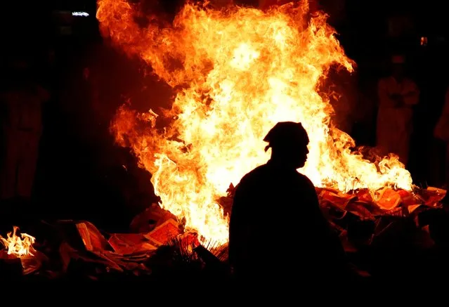 A Taoist devotee walks past a burning joss paper and sticks on the last day of the Nine Emperor Gods festival in Ampang, Malaysia on October 23, 2023. (Photo by Hasnoor Hussain/Reuters)