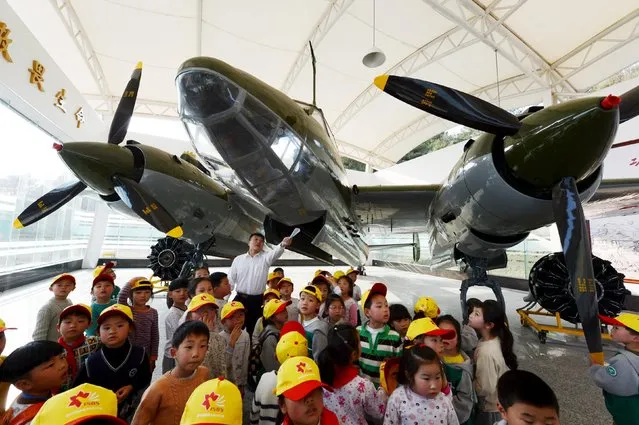A volunteer teaches aviation knowledge to primary school students at a college exhibition centre in Changsha, Hunan province, China, March 2, 2016. (Photo by Reuters/China Daily)