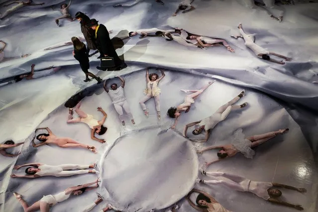 Patrons of the New York City Ballet walk past a massive photograph on linoleum flooring featuring over 80 dancers arranged in an array of poses at the David H. Koch Theater at Lincoln Center Tuesday, January 28, 2014, in New York. The work of French-born artist JR, winner of the 2011 TED Prize and known for his large-scale photography projects, was made by staging a photo shoot of the artists lying down pushing and pulling on a white crinkled paper. (Photo by AP Photo)