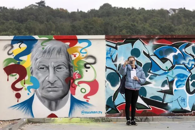 Essex live reporter Anna Willis conducts a facebook live broadcast beside a new piece of graffiti artwork depicting the late Sir David Amess, who was killed while conducting a surgery for constituents last week, on October 18, 2021 in Leigh-on-Sea, England. Sir David Amess, MP for Southend West, was stabbed to death while meeting with constituents in Leigh-on-Sea on Friday. A 25-year-old man, Ali Harbi Ali, was arrested at the scene and the attack is being treated by police as a terrorist incident. (Photo by Dan Kitwood/Getty Images)
