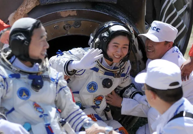 Liu Yang (C), China's first female astronaut, waves next to her comrade Jing Haipeng (L) as she comes out from the re-entry capsule of China's Shenzhou 9 spacecraft in Siziwang Banner, Inner Mongolia Autonomous Region June 29, 2012. The mission put the country's first woman in space and completed a manned docking test critical to its goal of building a space station by 2020. (Photo by Reuters/China Daily)