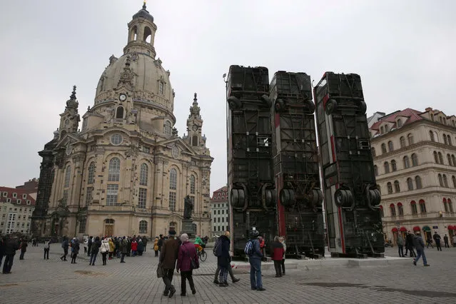 People walk next to the art instalation “Monument” by Syrian artist Manaf Halbouni, made from three passenger busses in Dresden, Germany February 8, 2017. (Photo by Matthias Schumann/Reuters)