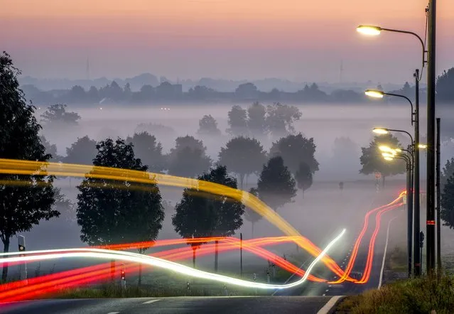 A long time exposure photo shows cars driving through the fog on the outskirts of Frankfurt, Germany, Thursday, September 23, 2021. (Photo by Michael Probst/AP Photo)
