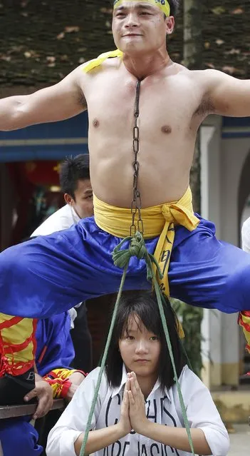 Nguyen Manh Quan (top), 26, a civil servant, carries a girl using his throat area as he performs during a showcase of the traditional Thien Mon Dao kung fu at Du Xa Thuong village, southeast of Hanoi, Vietnam May 10, 2015. (Photo by Reuters/Kham)
