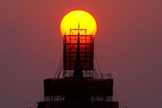 The sun sets behind the Wat Saket Temple's Golden Mount, which is undergoing renovation, in Bangkok, Thailand on March 18, 2024. (Photo by Athit Perawongmetha/Reuters)