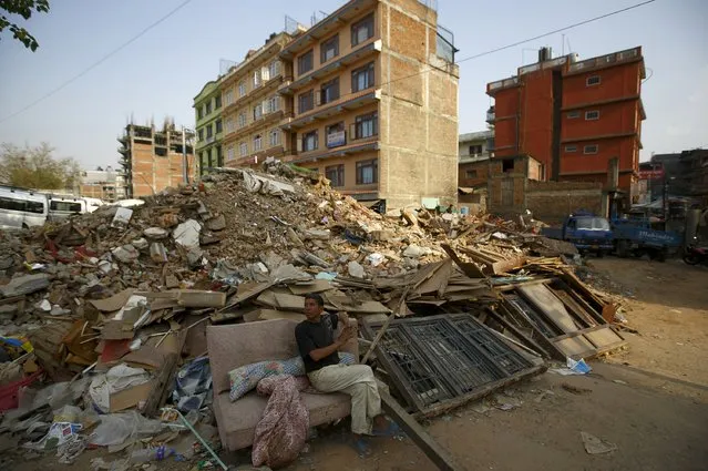 A man sits on the couch near the debris of the collapsed houses, a month after the April 25 earthquake in Kathmandu, Nepal May 25, 2015. (Photo by Navesh Chitrakar/Reuters)