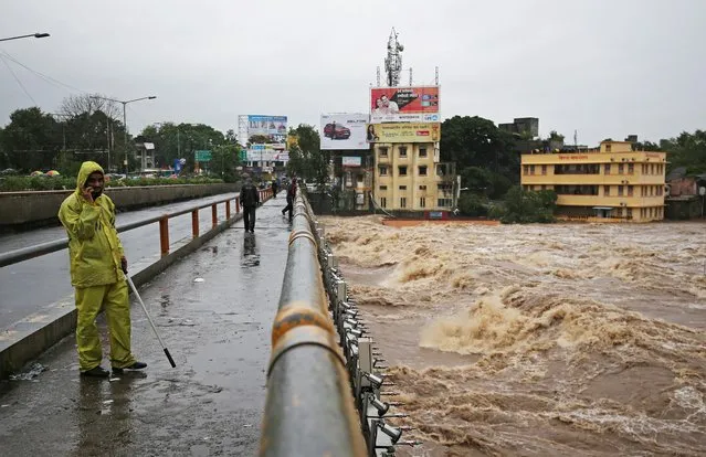 A policeman stands on a bridge as houses are seen submerged in the waters of overflowing river Godavari after heavy rainfall in Nashik, India, August 4, 2019. (Photo by Francis Mascarenhas/Reuters)