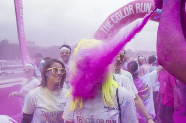 A runner is sprayed with purple powder during the Color Run race in Paris, on April 13, 2014. The Color Run is a five kilometres paint race without winners nor prizes, while runners are showered with colored powder at stations along the run. (Photo by Fred Dufour/AFP Photo)