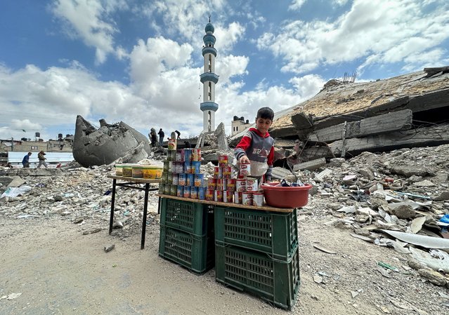 A boy stands next to canned food on the day of Friday prayers during the holy fasting month of Ramadan, amid the ongoing conflict between Israel and the Palestinian Islamist group Hamas, in Rafah, in the southern Gaza Strip, on March 22, 2024. (Photo by Mohammed Salem/Reuters)