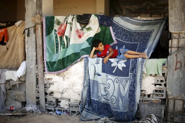 A Palestinian boy lies at his family's house, that witnesses said was damaged by Israeli shelling during a 50-day war last summer, in the east of Gaza City June 26, 2015. Picture taken June 26, 2015. (Photo by Mohammed Salem/Reuters)